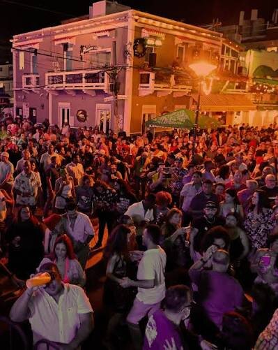 A crowd filling the street at night in front of a lit pastel building at La Placita de Santurce